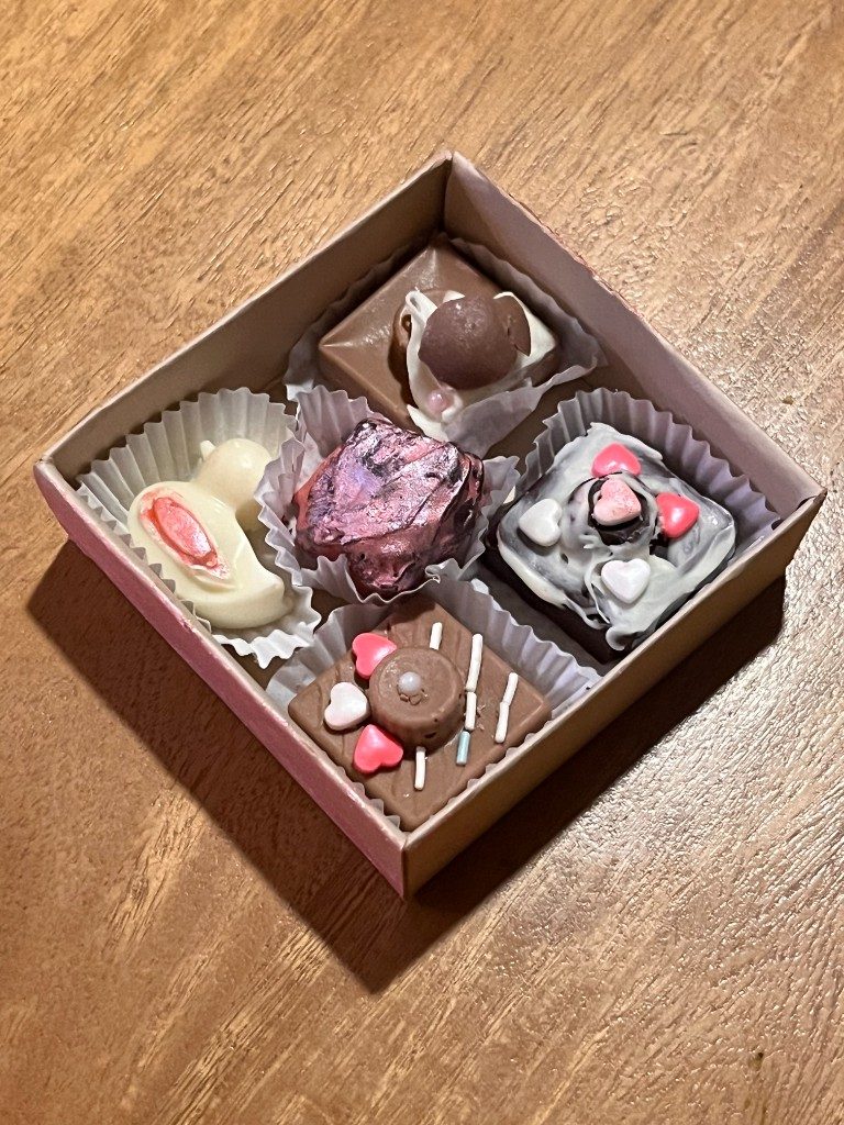 Magic Box abierta de Chocolombia con cinco bombones decorados sobre una mesa de madera