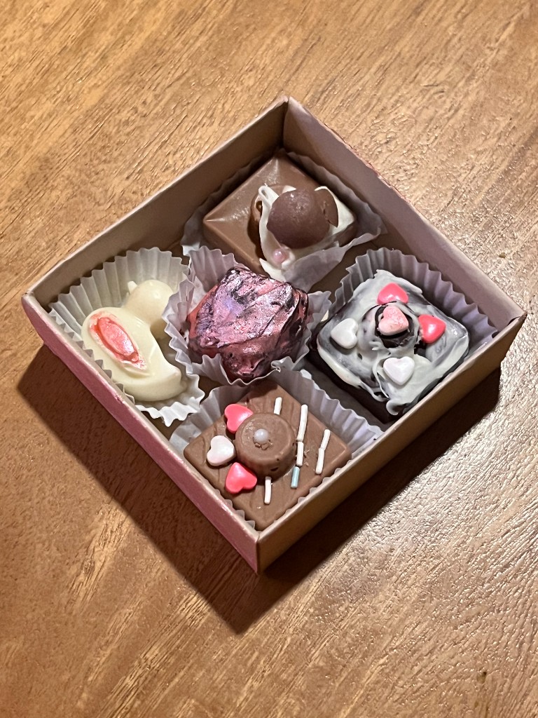 Magic Box abierta de Chocolombia con cinco bombones decorados sobre una mesa de madera